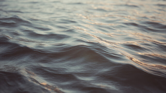 Serene close-up view of gentle waves rippling on the water surface, reflecting soft light, creating a peaceful atmosphere.