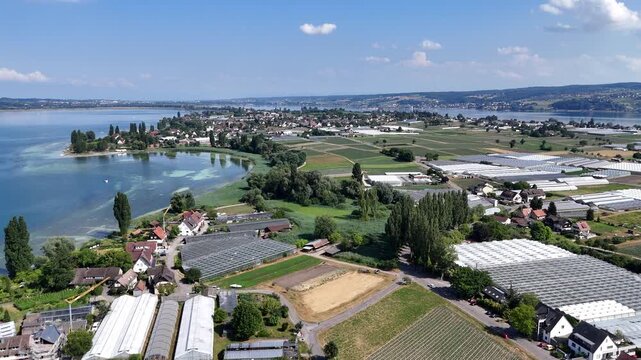 Panorama flight over island Reichenau with houses, fields and greenhouses next to Lake Constance (Bodensee) near Konstanz, Germany