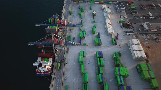 Mercante cargando contenedores con gr&uacute;as en puerto para transporte mar&iacute;timo, cenital a&eacute;reo  , barco porta contendores