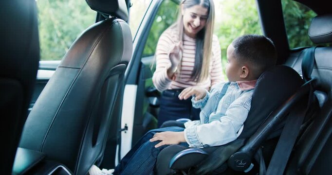 Family, mom and fasten child car seat for safety, support and high five with boy or travel with kid. Happy, woman and celebration for secure seatbelt in vehicle, protection and road trip with son