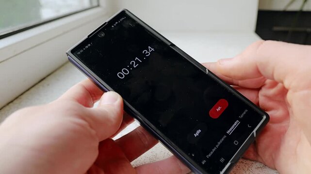 Close up view of male hands using smartphone timer near window in indoor