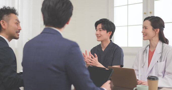 クリニックの会議室で打ち合わせをする若い医師とビジネスマン