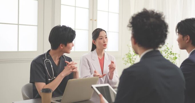クリニックの会議室で打ち合わせをする若い医師とビジネスマン