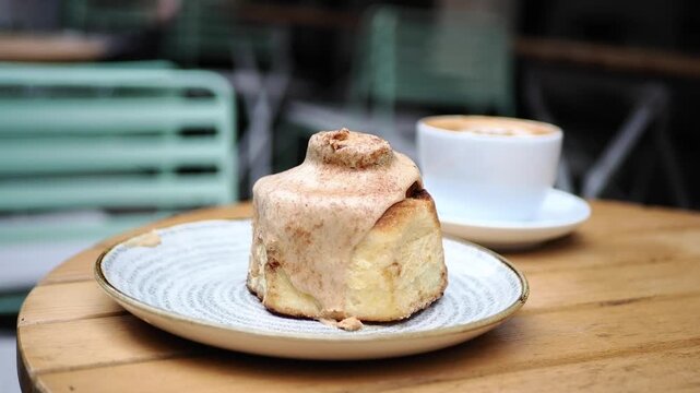 Enjoying cinnamon roll and coffee at a cafe in the morning