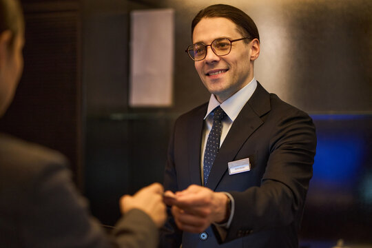 Caucasian hotel receptionist handing key card to guest during check in, supporting hospitality service and customer care. Useful for travel booking, tourism, concierge marketing