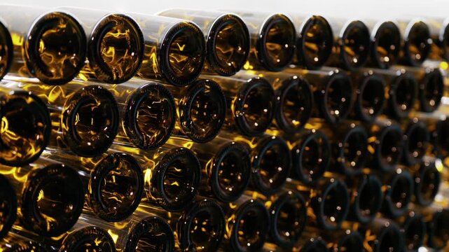 Rows of empty amber glass bottles stacked on storage racks in production factory.