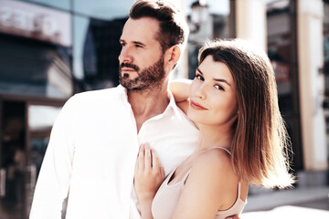 Naklejka premium Beautiful fashion woman and her handsome elegant boyfriend in white shirt. Sexy brunette model in summer clothes. Fashionable smiling couple posing in street Europe. Brutal man and female outdoors