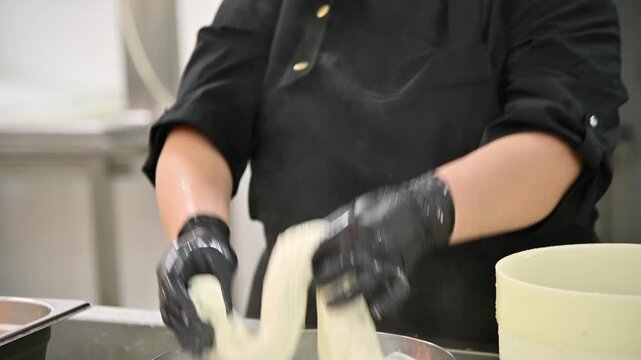 Chef prepares stracciatella cheese by stretching and shaping curds in kitchen