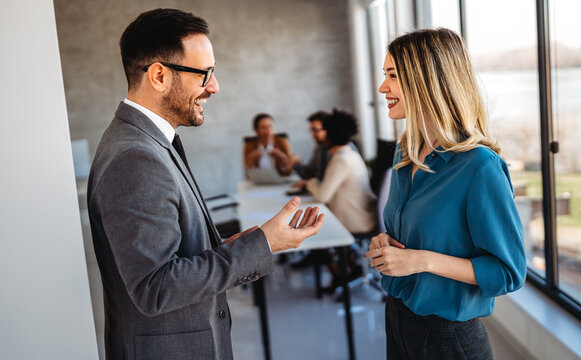 Portrait of successful business people working, talking together in corporate office during work.