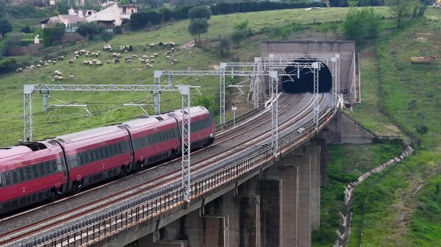 Treno ad alta velocit&agrave; attraversa un ponte e entra in una galleria. Italia.
Vista aerea di un treno tra le campagne romane.