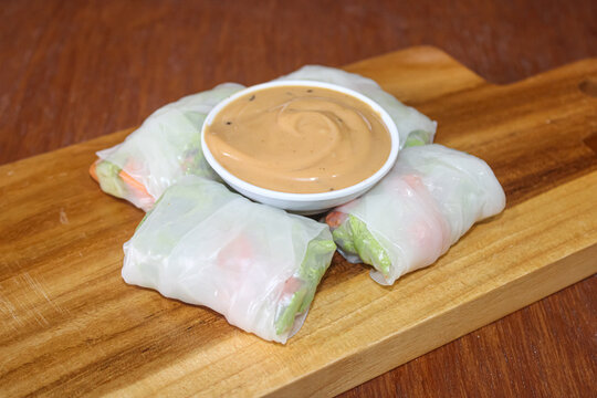 Fresh Vietnamese spring rolls with peanut dipping sauce on wooden board