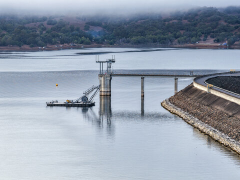 Aerial view of the Glenbawn Dam wall featuring the water intake system and servicing pontoon in NSW Australia. Drone photograph captures the engineering infrastructure, reservoir waters