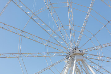 Fototapeta premium Low-angle view of giant white Ferris wheel under bright blue sky