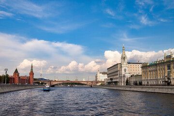 Fototapeta premium Bright sky over the Moscow river shows a boat passing by. The buildings along the river feature historical architecture. The scene captures an outdoor view of the city.