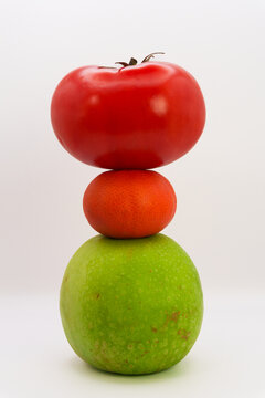Mandarin, apple, tomato and sweet pepper in the form of a tower on a white background, the concept of healthy eating from fruits and vegetables, health care, fruit diet, vegans and vegetables. High qu