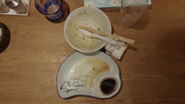 Top view of empty ramen bowl and dipping plate with chopsticks after meal at Japanese restaurant