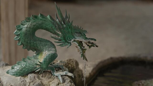 Green oxidized dragon statue spouting water for chozuya purification ritual at Japanese shrine