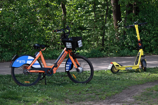 MOSCOW, RUSSIA - MAY 15, 2026: Orange Velobike electric bicycle and yellow Yandex Go scooter in a Moscow park
