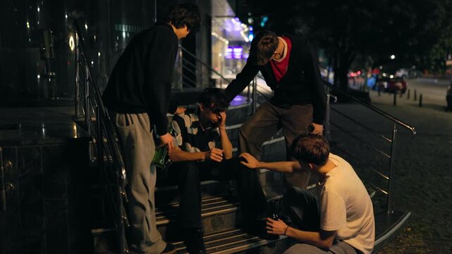 Wide shot of four teenage friends supporting a crying companion on stairs.