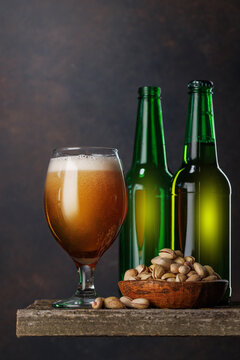 Beer glass with foam and bottles with pistachios