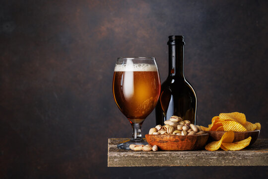 Beer glass with foam and bottle with pistachios