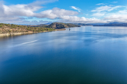 Aerial view of the Glenbawn Dam wall and surrounding landscape showcasing the expanse of the dam in NSW Australia. Drone photograph captures the large reservoir, rugged mountain scenery