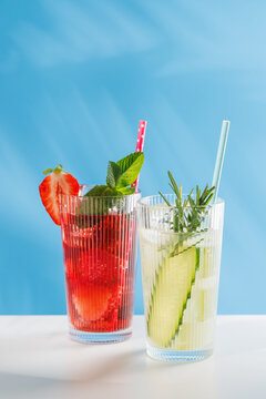 Colorful non alcoholic summer drinks with strawberry and cucumber on blue background