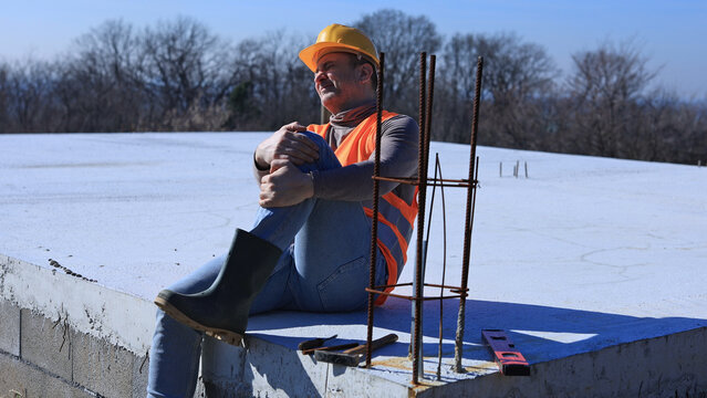 Construction worker having a accident and injured knee and leg on a construction site outdoors.