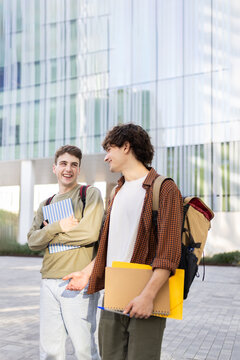 Two happy students walking and talking on university campus