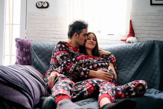 A couple kisses on the sofa at home during the Christmas holidays.