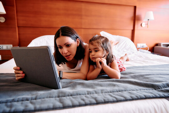 Little girl and her mother using an iPad in a hotel room