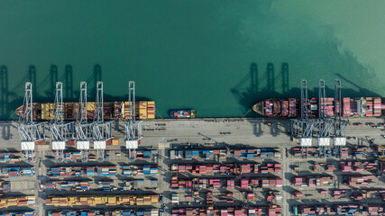 Aerial drone shot of crane loading containers onto cargo ship at Laem Chabang Port. © Nutchanart
