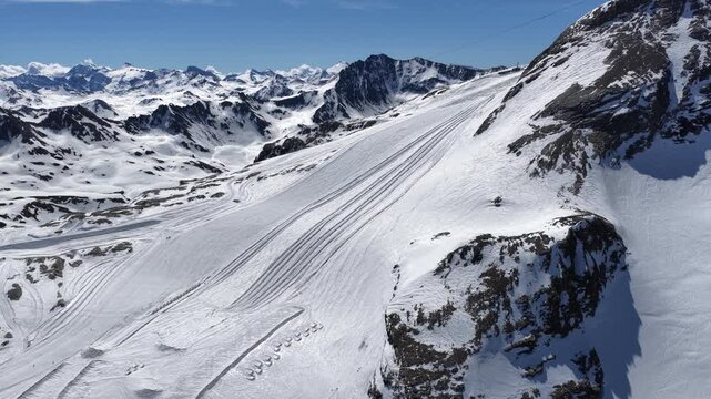 Sunny drone view of Tignes and Grande Motte glacier surrounded by snowy mountains in the French Alps during spring. Drone view of alpine glacier and snowy mountain peaks in French Alps