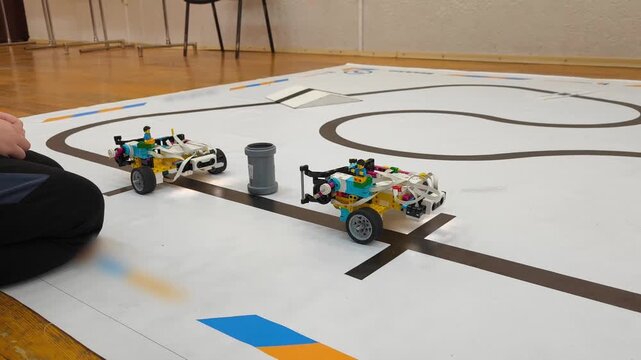 Low angle - two robots are standing at the start line of a training track for competitions in robotics, STEM, programming, engineering training.
