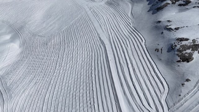 Sunny drone view of Tignes and Grande Motte glacier surrounded by snowy mountains in the French Alps during spring. Drone view of snowboarders and skiers riding on glacier in French Alps