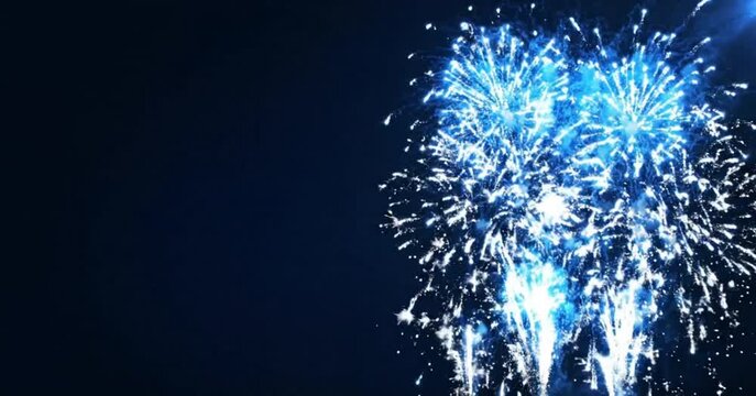 Spectacular blue and white fireworks exploding in the dark night sky with copy space for celebration and festive events