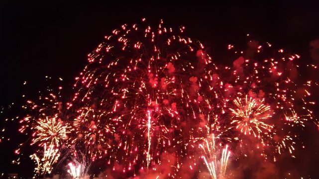 Vibrant fireworks exploding in the night sky with bright orange and yellow lights
