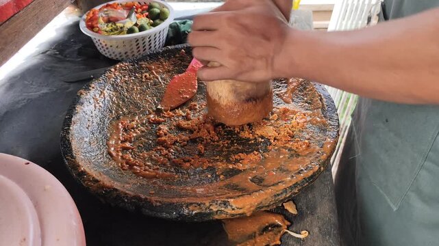 indonesian street food Gado-gado, grinding peanut sauce using traditional stone mortar and pestle close up