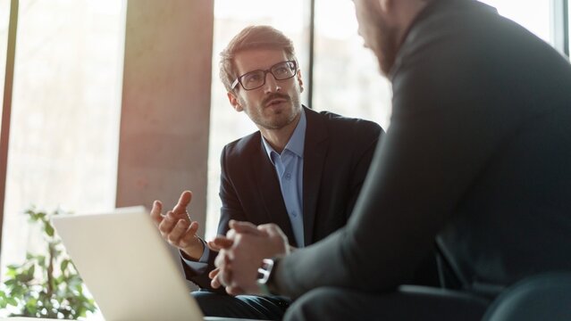 Businessmen discussing deal, sharing startup ideas, business partners negotiations or job interview in modern office