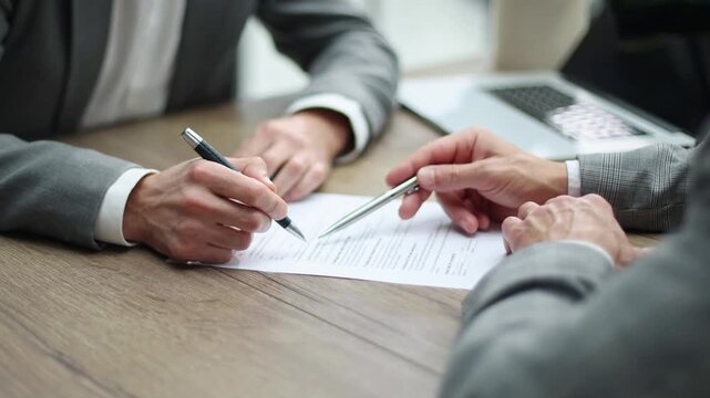 Two professionals sit at a wooden table