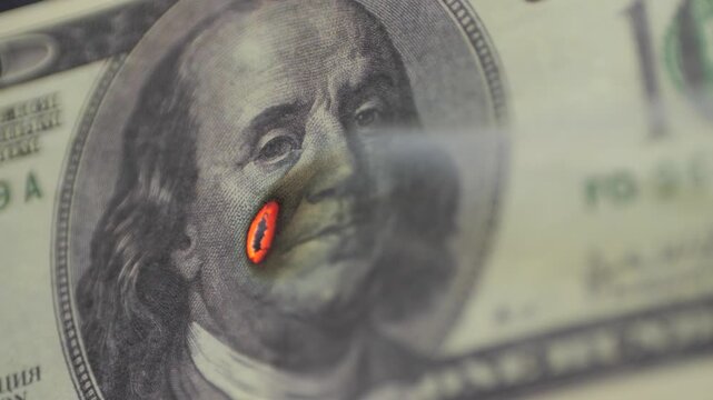 Money is burning. 100 dollar bill is slowly burning. Loss of money, financial losses, economic crisis concept.
