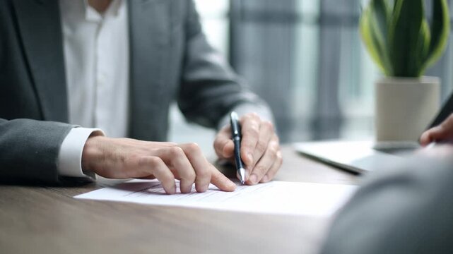 Businessman signs contract with focused expression