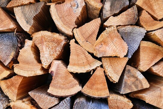 Stacked Firewood Background: Close-up Texture of Split Pine Logs with Visible Annual Growth Rings