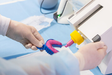 Fototapeta premium Pink impression material dispensed onto a dental tray in gloved hands, showing clean clinical preparation with blue drape automatic mixer nozzle and soft shallow focus nearby supplies