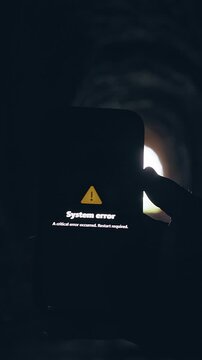 Vertical video. Smartphone Displaying System Error Message Inside Dark Tunnel, Cinematic Technology Failure Scene About Digital Malfunction and Communication Breakdown