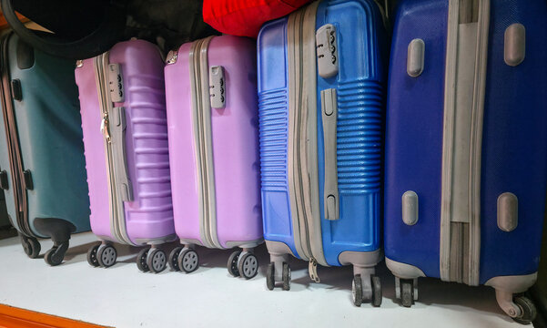 Colorful hard-shell suitcases lined up against a wall, showcasing various sizes and designs, with wheels and zippers visible. Things for traveling