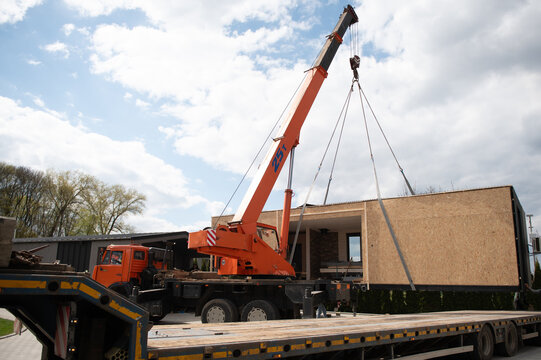Modular home being lifted by crane during transportation