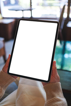 Vertical mockup image of a woman holding digital tablet with blank white desktop screen in cafe
