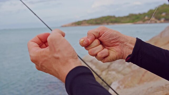 Close Up First Person View of Hands Preparing Transparent Fishing Line on Rocky Tropical Coastline, Recreational Fishing and Outdoor Adventure