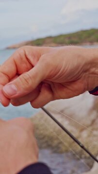 Vertical video. Close Up First Person View of Fishing Sinker Hanging on Transparent Line Near Tropical Rocky Coast, Saltwater Fishing and Marine Recreation